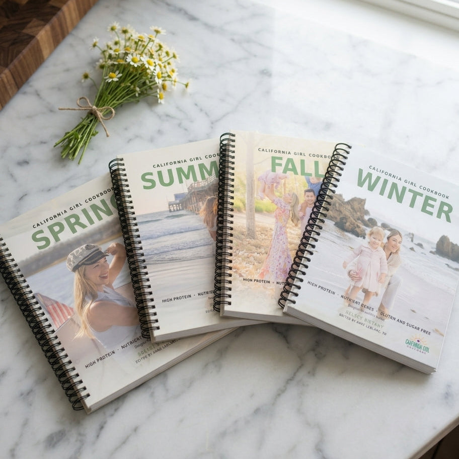 All 4 California Girl Cookbook seasonal spiral-bound cookbooks on marble countertop
